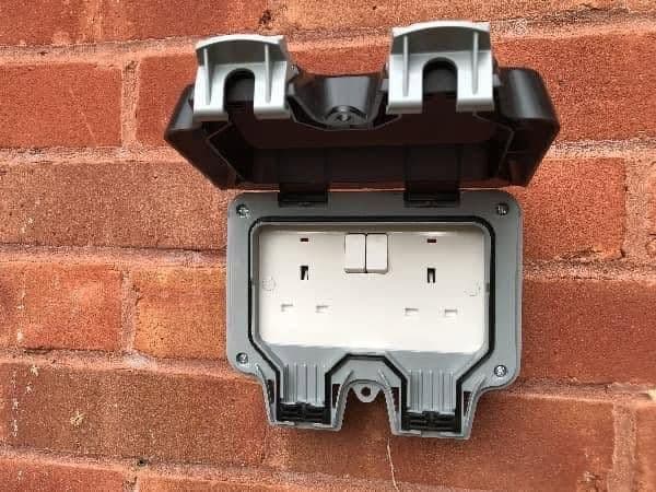 Weatherproof outdoor double socket fitted to a brick wall