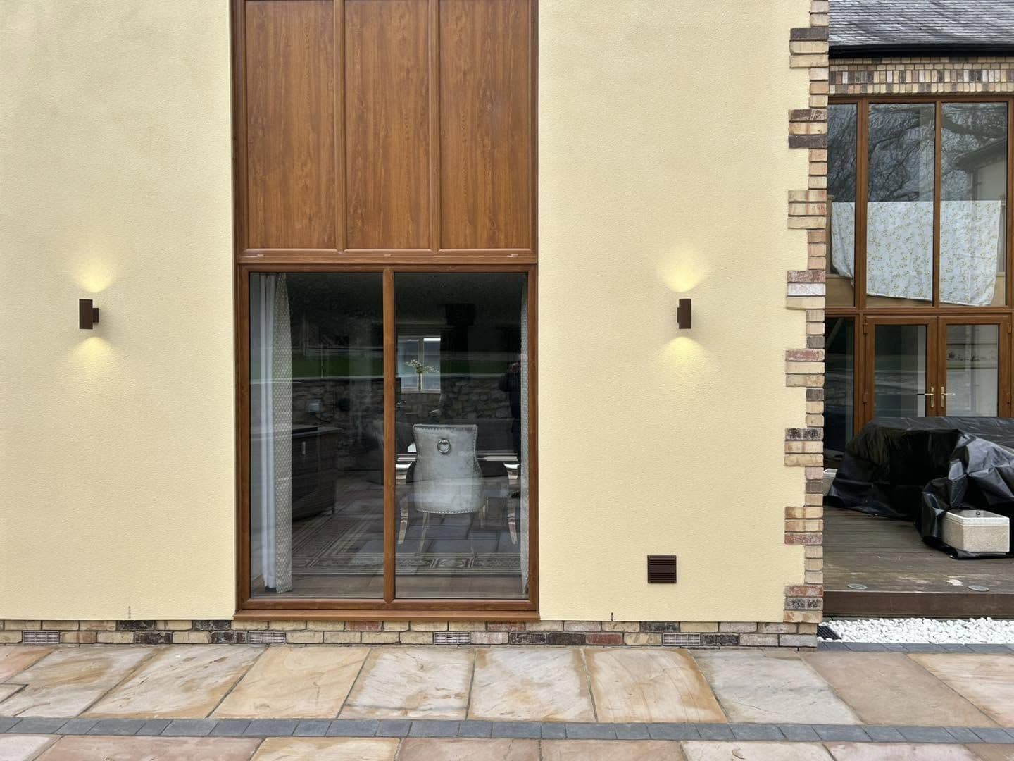 Up-and-down wall lights fitted either side of patio doors on a smart rendered home
