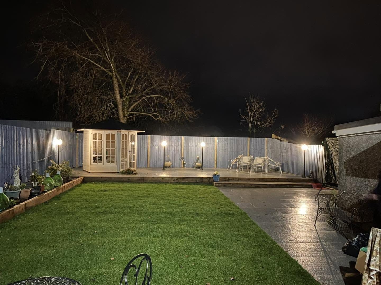 Summerhouse and post lights lighting a landscaped garden at night